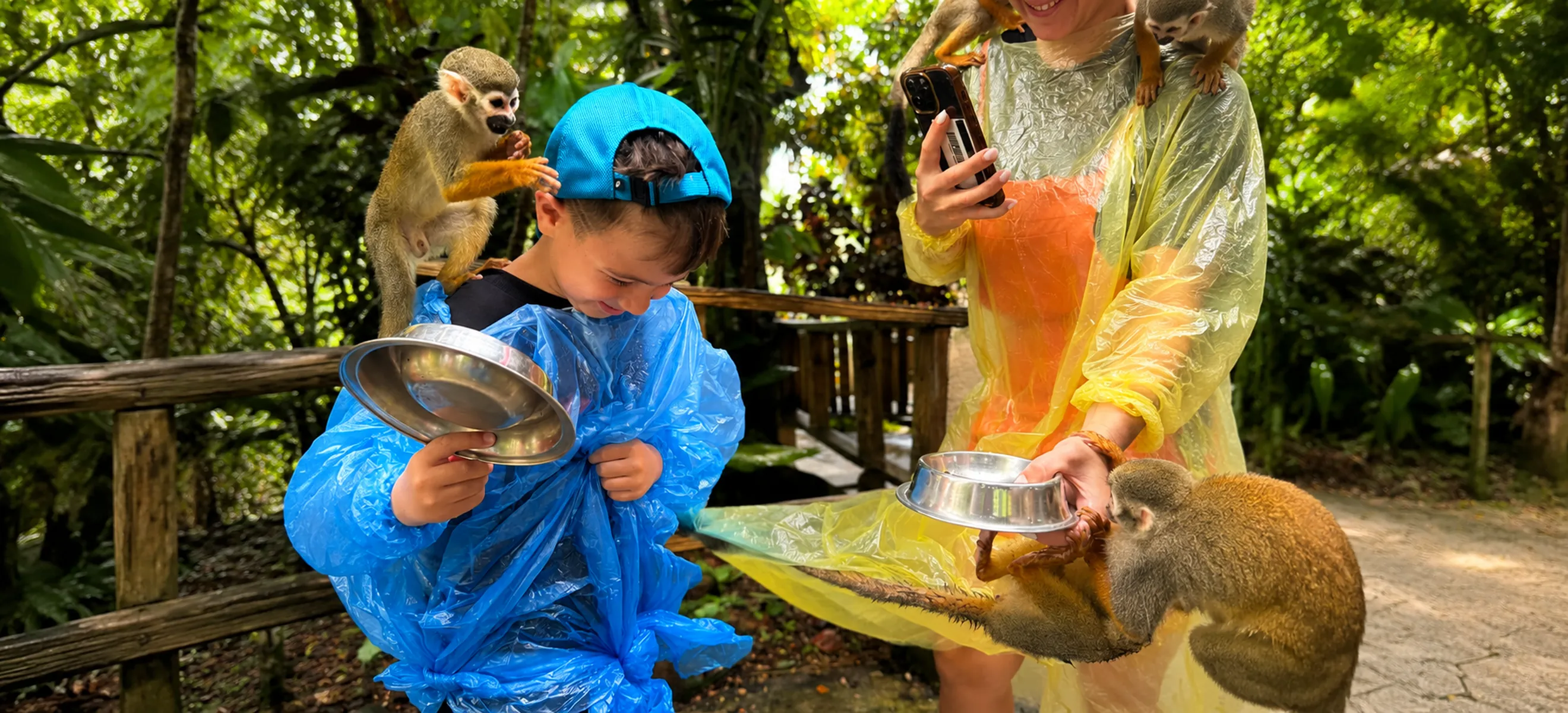 	Young child and parent enjoying a close interaction with friendly squirrel monkeys during the Monkeyland Punta Cana family wildlife adventure in the Dominican Republic.