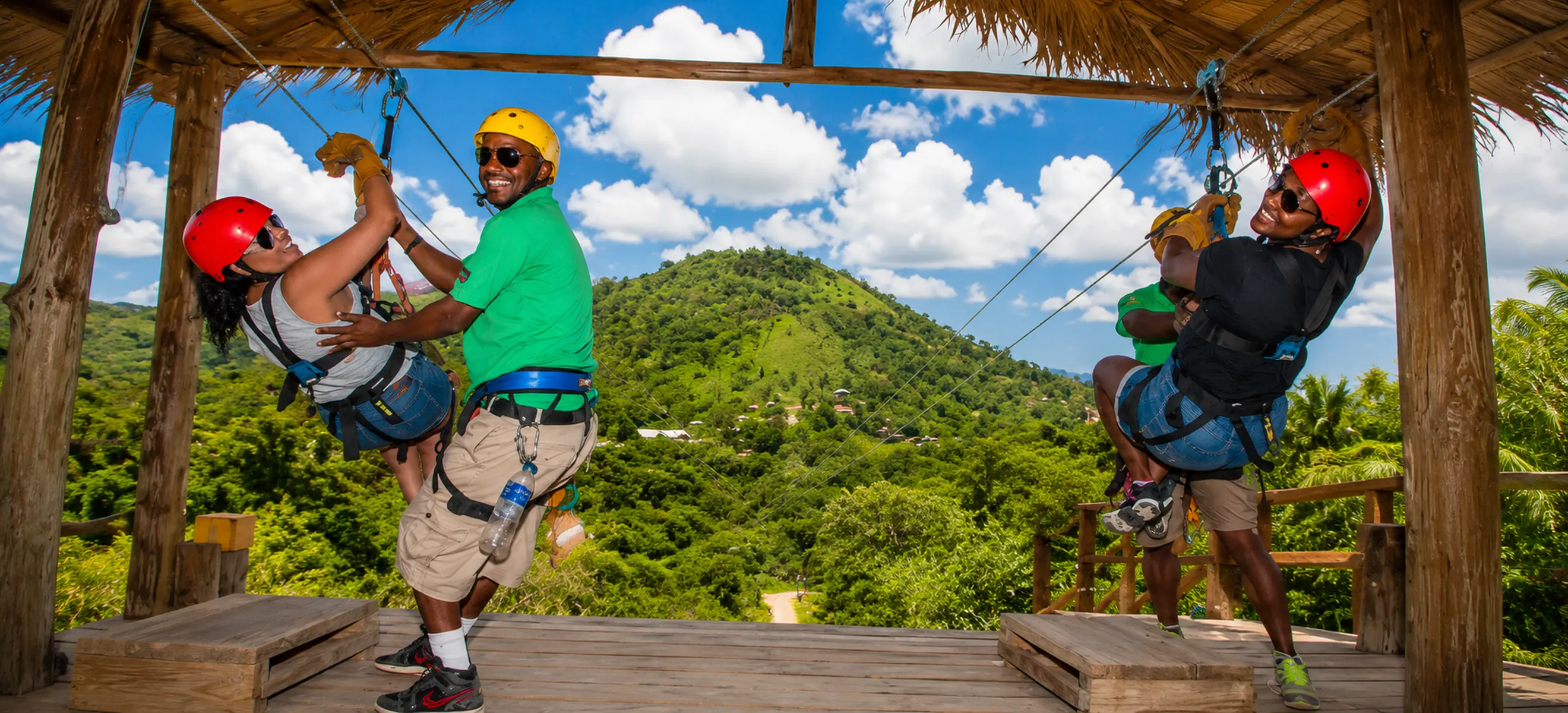 	Professional guides assisting guests on the zipline launch platform during the Monkeyland & Zipline Adventure Punta Cana, overlooking the lush Dominican rainforest and mountain scenery.