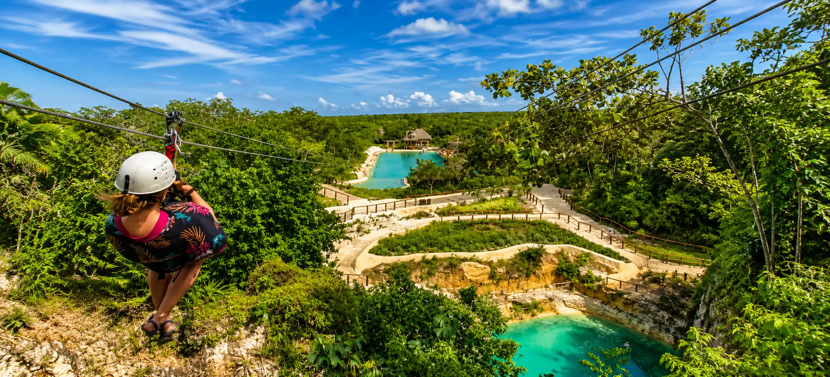 Guest soaring on the Scape Park Cap Cana zipline above lush tropical jungle and turquoise lagoons during an eco-adventure in Punta Cana, Dominican Republic.